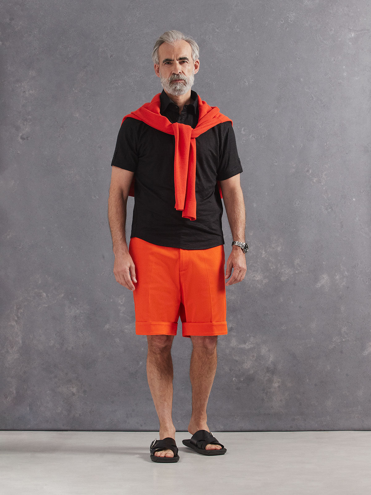 Madeira French Linen Short Sleeve Polo in *Berlin Black* (black) styled with Aperol Orange Becker Short and Aperol Orange Dwayne V-Neck Cashmere Sweater on shoulders — full length lookbook | Y.Chroma